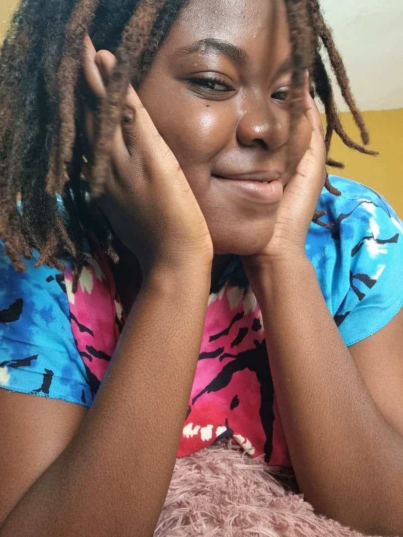 Sika Reine, les deux mains posées contre ses joues, le visage tourné de côté